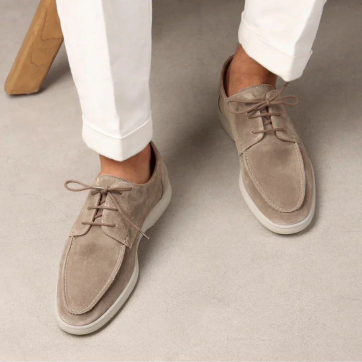 Beige suède herenschoenen, Vilano model, met veters en witte zool, gedragen met witte broek. Stijlvolle casual schoenen voor herenmode.