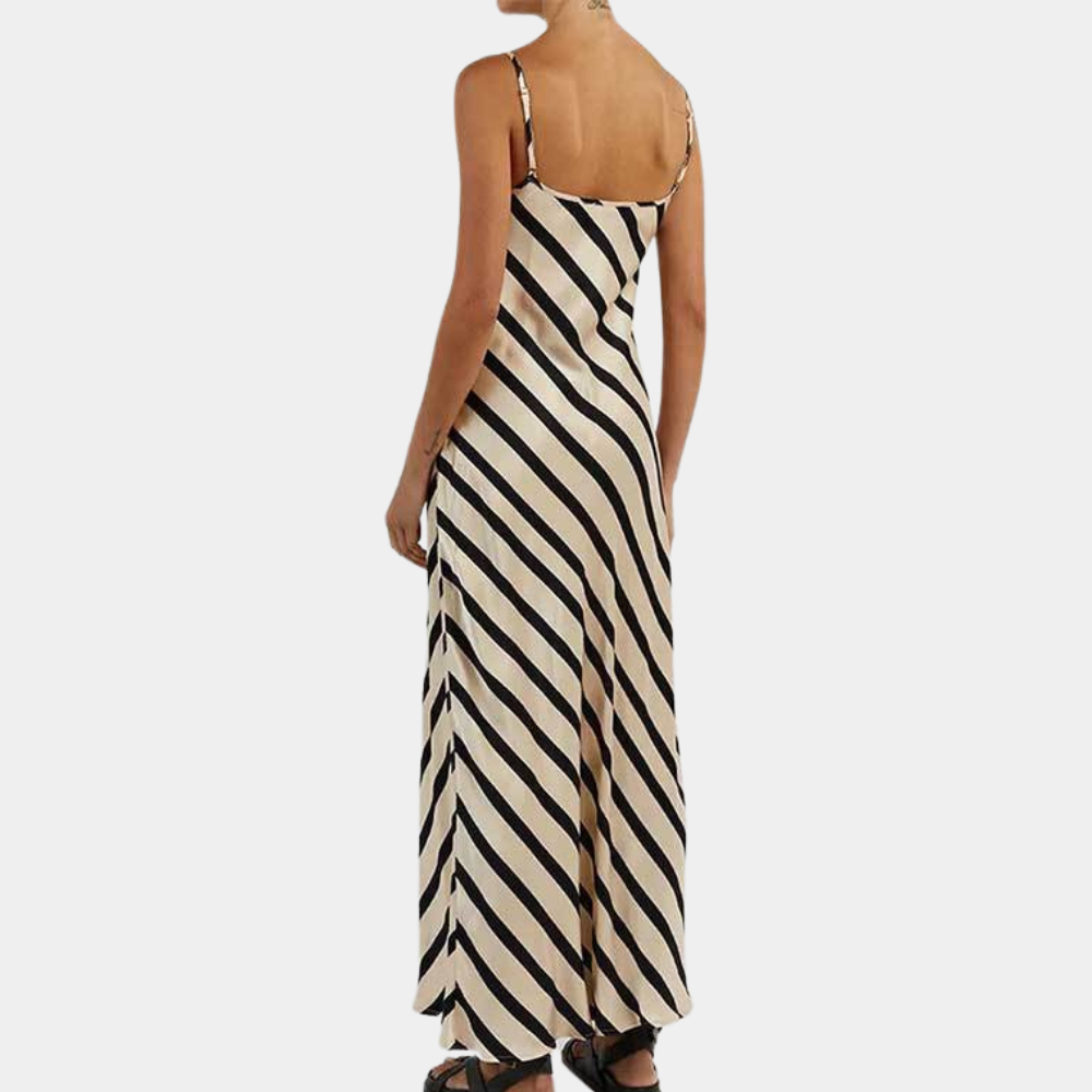 Vrouw in lange, mouwloze jurk met zwart-witte diagonale strepen, elegante zomerjurk, modetrend, casual stijl, achterkant zichtbaar.