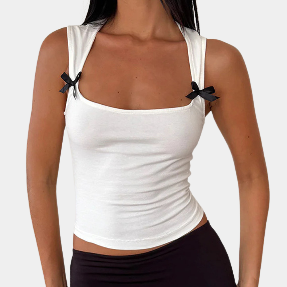 Vrouw draagt witte tanktop met zwarte strikjes, mouwloos ontwerp, modieuze dameskleding, casual stijl, perfect voor zomeroutfits.