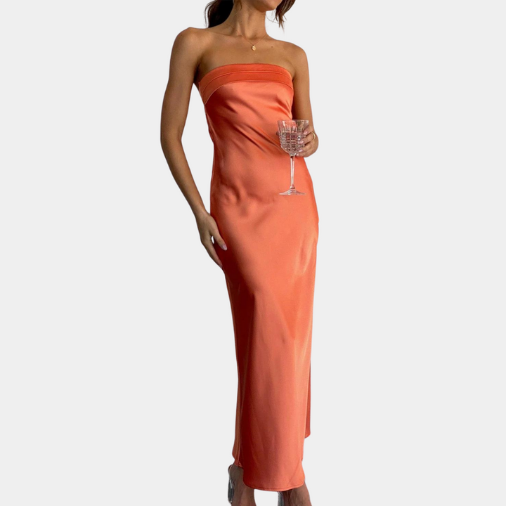 Vrouw in strapless oranje satijnen jurk met wijnglas, elegante avondkleding, modetrend, feestelijke outfit, stijlvolle damesmode.