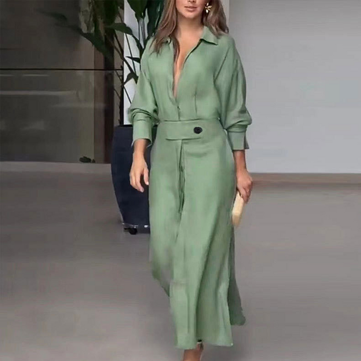Vrouw in groene maxi-jurk met lange mouwen en diepe V-hals, loopt binnen. Stijlvolle mode, elegante dameskleding, trendy outfit.