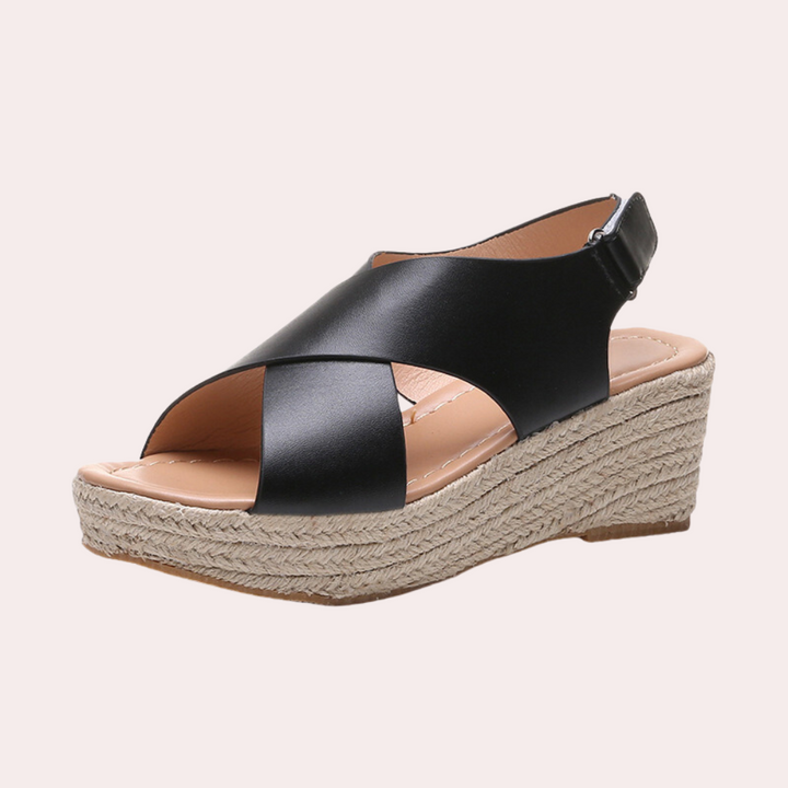 Zwarte dames espadrille sandaal met sleehak, gevlochten touwzool en leren kruisbanden. Comfortabele zomerschoen voor casual en elegante outfits.