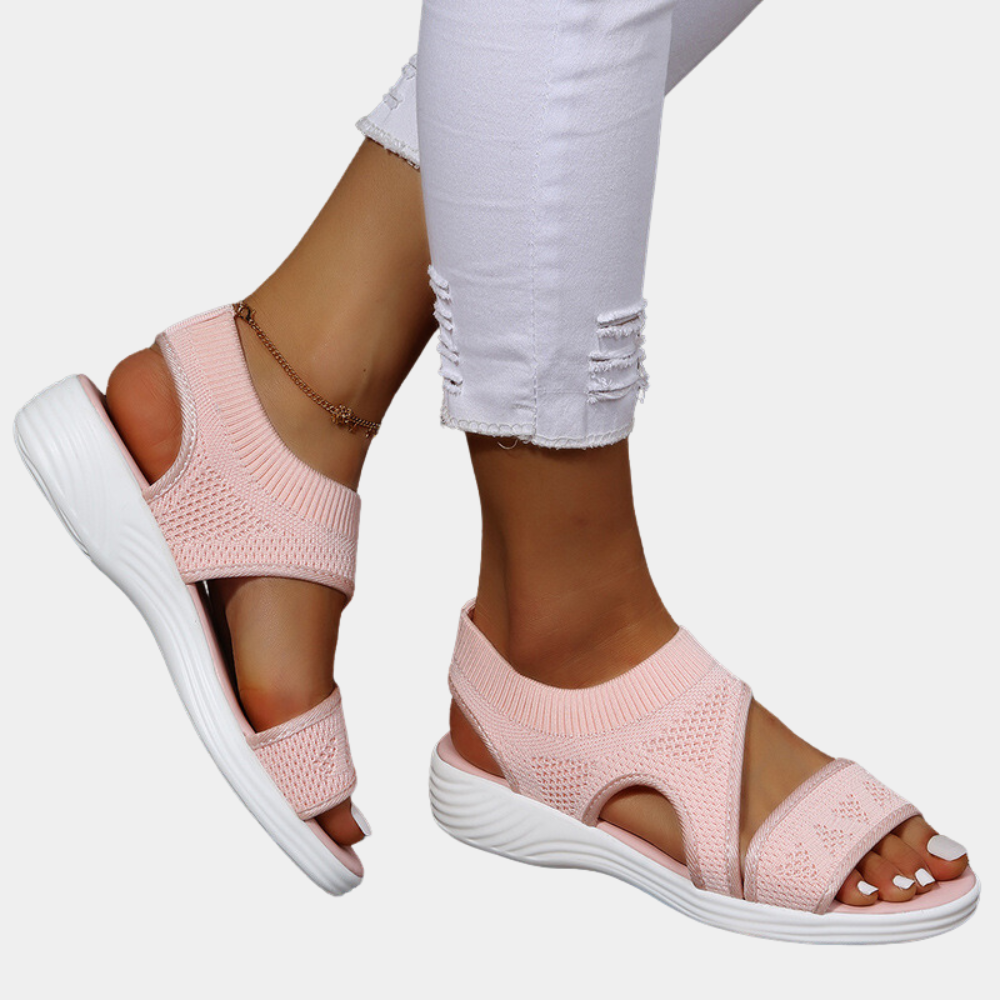Roze dames sandalen met gebreide bovenkant en witte zool, gedragen met witte gescheurde jeans. Comfortabele zomerschoenen voor dagelijks gebruik.