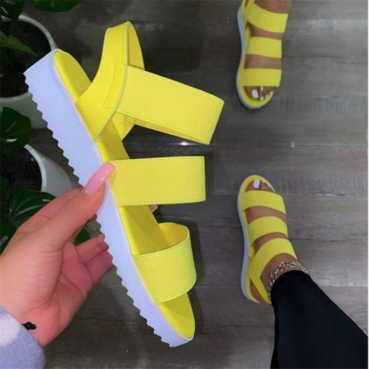 Heldere gele sandalen met witte zool, gedragen door een persoon op houten vloer. Trendy zomerschoenen, comfortabel en stijlvol voor dagelijks gebruik.