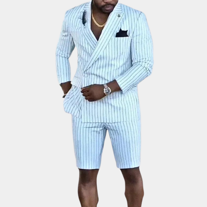 Man in gestreept wit pak met korte broek, gouden ketting en horloge. Stijlvolle herenmode, zomerse outfit, formele kleding.