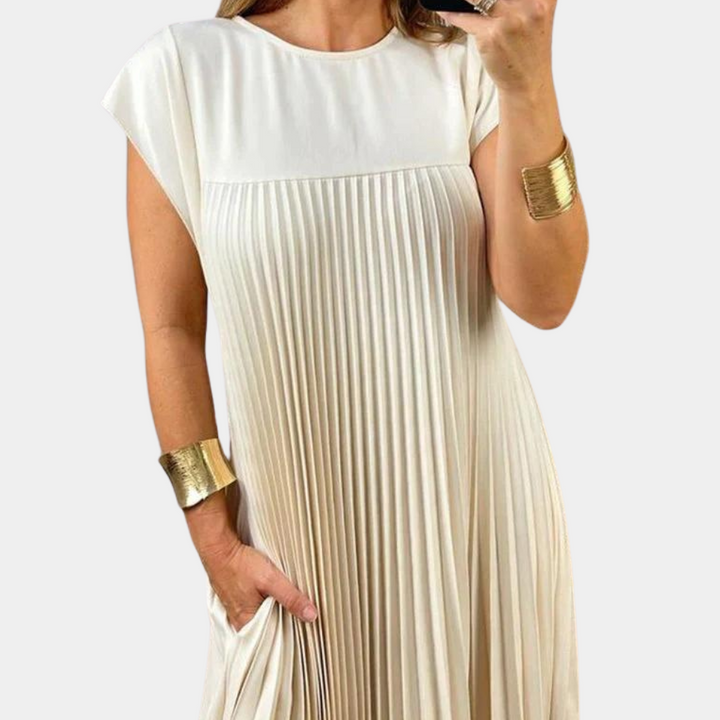 Vrouw in elegante, witte geplooide jurk met korte mouwen en gouden armbanden. Modieuze dameskleding, zomerjurk, casual chic stijl.