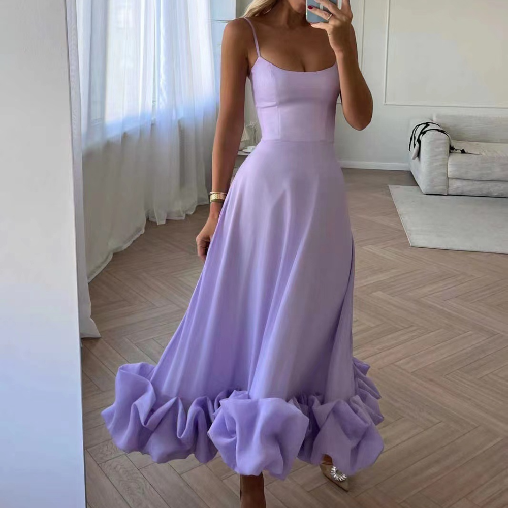 Vrouw in elegante paarse jurk met ruches, staand in moderne woonkamer. Trendy avondjurk, perfect voor speciale gelegenheden.