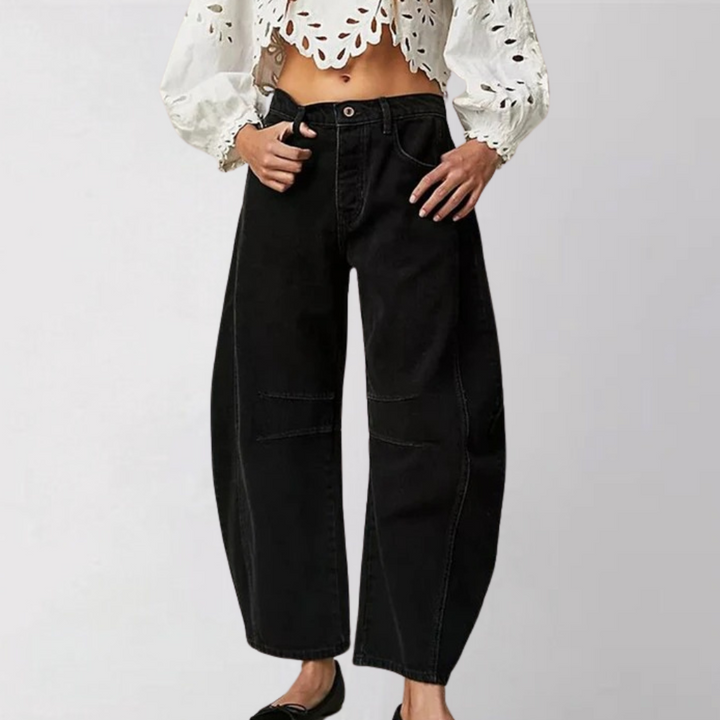Zwarte wijde jeans met hoge taille, gedragen door model met witte kanten blouse. Trendy damesmode, comfortabele pasvorm, casual stijl.
