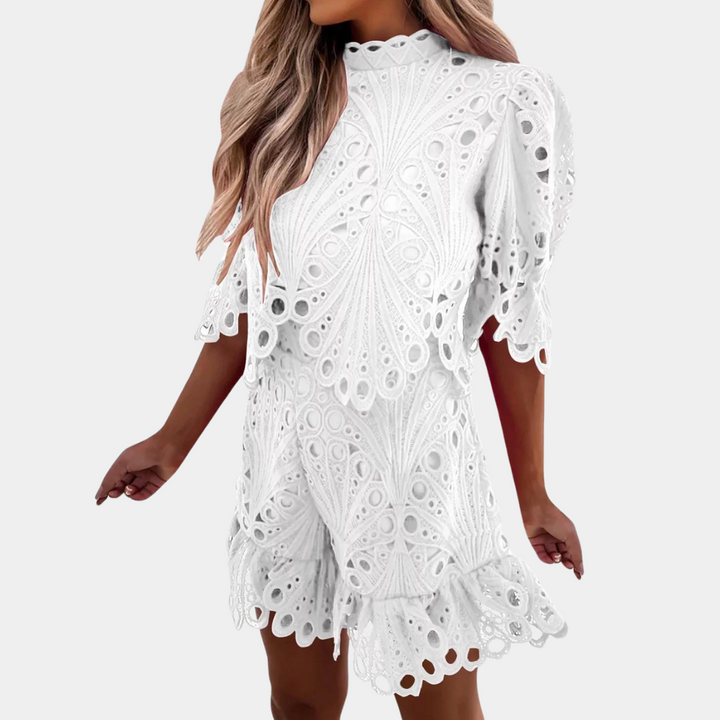 Vrouw in witte kanten jurk met korte mouwen en golvende zoom, perfect voor zomermode. Elegante en stijlvolle dameskleding.