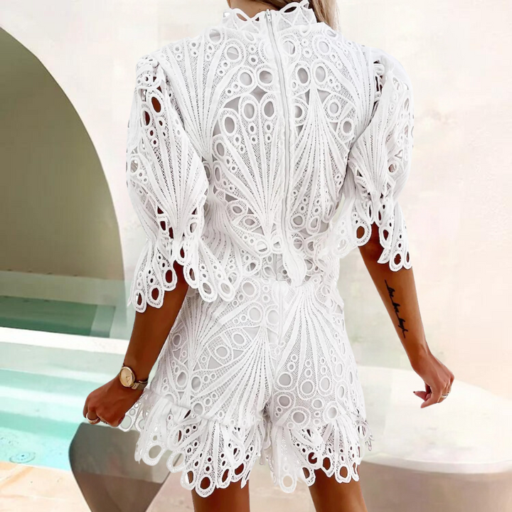 Witte kanten jurk met korte mouwen en opengewerkt patroon, gedragen door vrouw bij zwembad. Zomerjurk, elegante damesmode, trendy kleding.