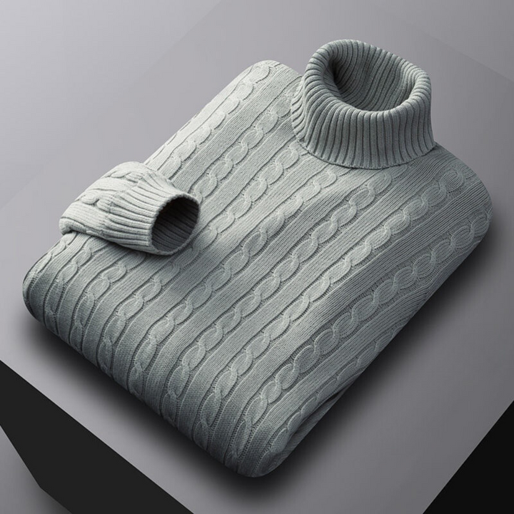 Lichtgrijze kabeltrui met col, opgevouwen op een grijze achtergrond. Stijlvolle herentrui, warme wintermode, gebreide kleding.