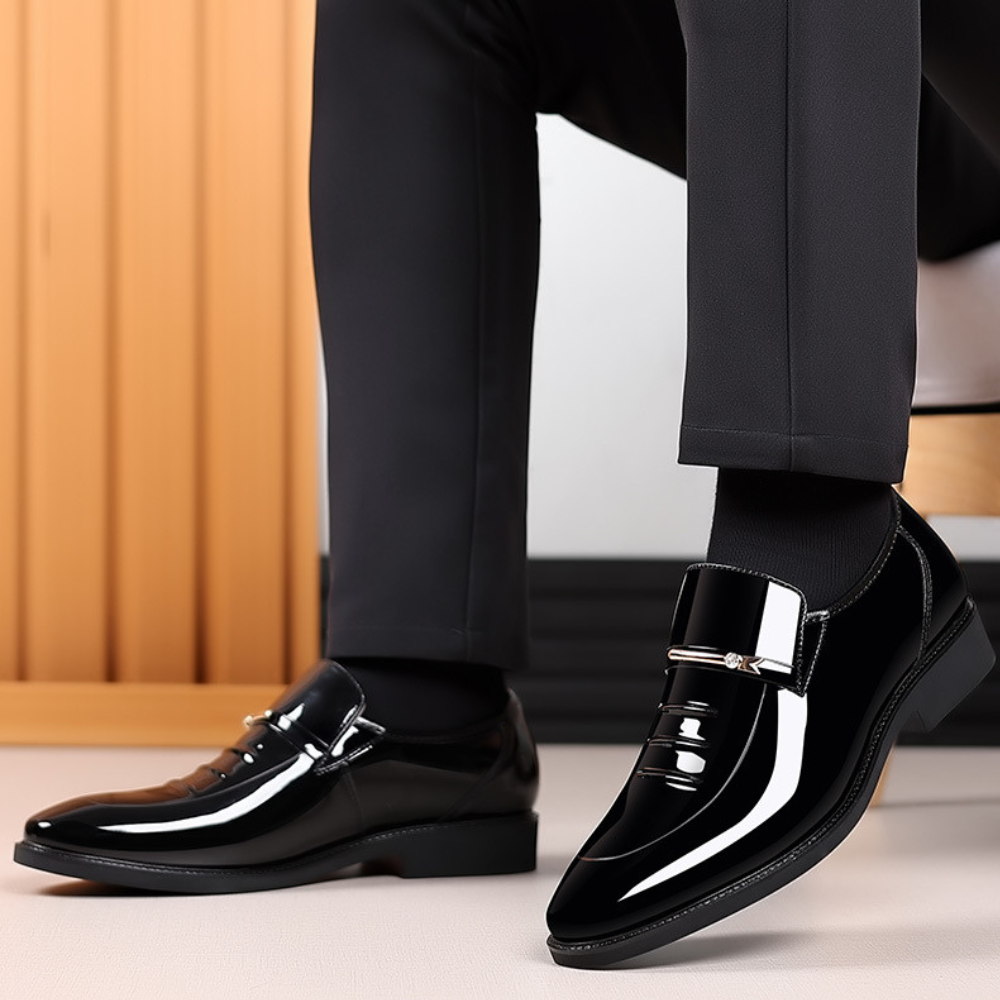 Zwarte leren herenschoenen met glanzende afwerking en gesp, gedragen met zwarte broek. Stijlvolle formele schoenen voor herenmode.