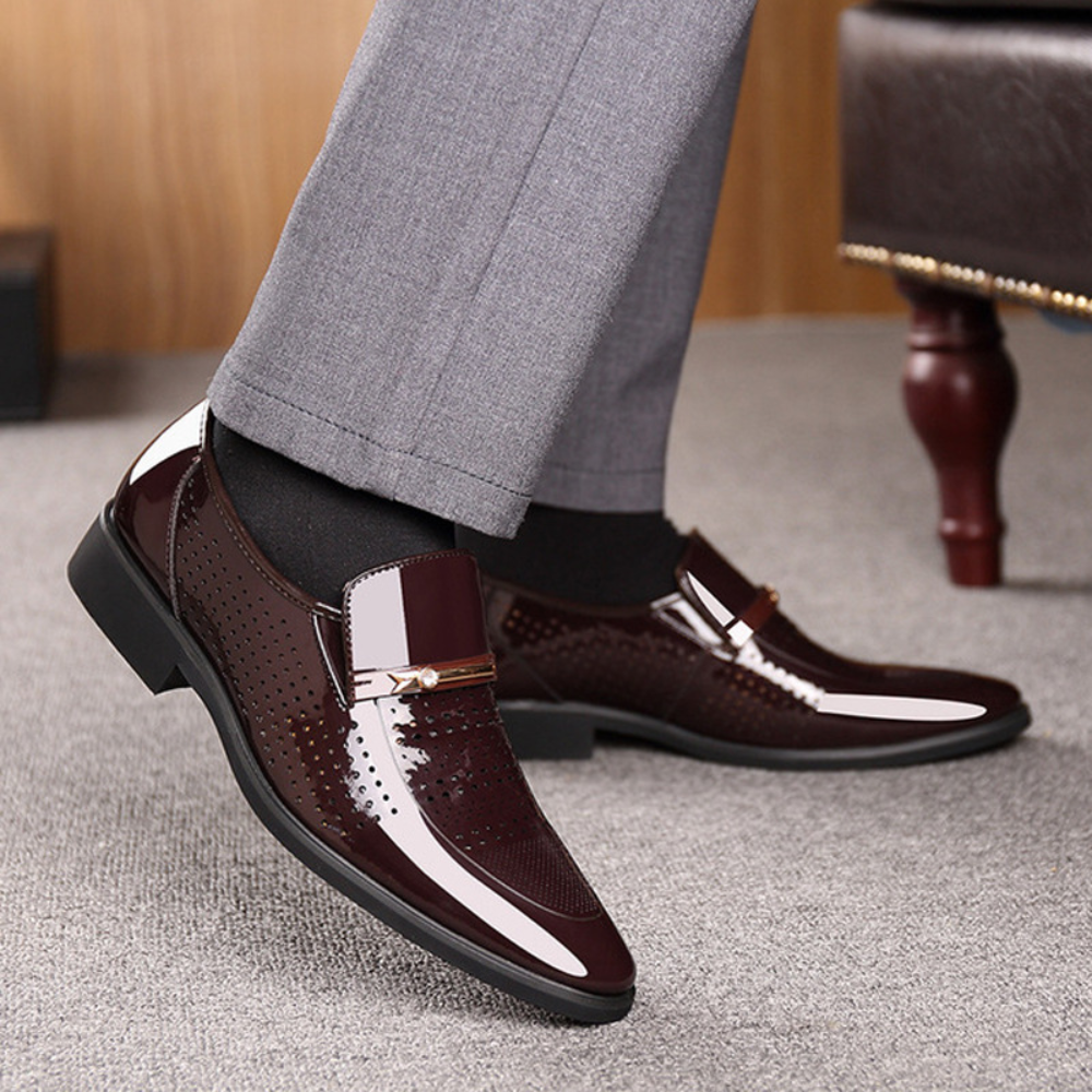 Bruine leren herenschoenen met glanzende afwerking en metalen gesp, gedragen met grijze broek. Stijlvolle formele schoenen voor herenmode.