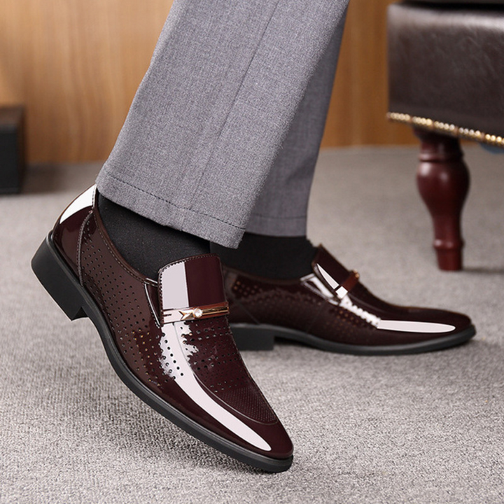 Bruine leren herenschoenen met glanzende afwerking en metalen gesp, gedragen met grijze broek. Stijlvolle formele schoenen voor herenmode.