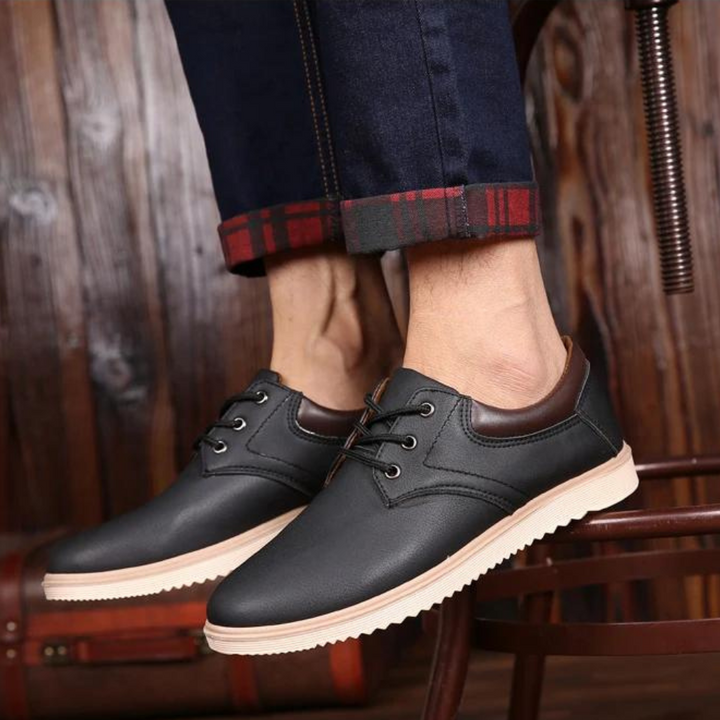 Zwarte leren herenschoenen met bruine accenten, casual stijl, gedragen met opgerolde jeans. Perfect voor modieuze, comfortabele herenschoenen.