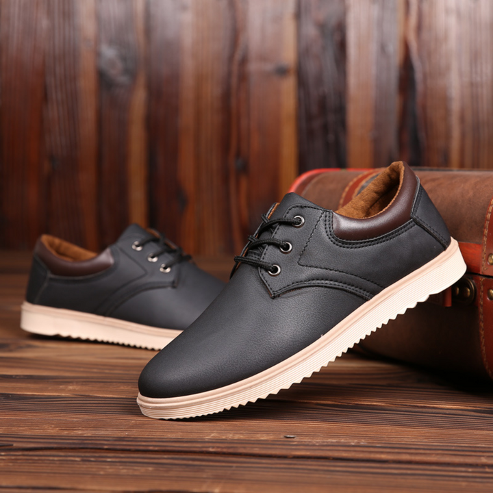 Zwarte leren herenschoenen met bruine accenten, casual stijl, op houten vloer. Comfortabele veterschoenen, perfect voor dagelijks gebruik.