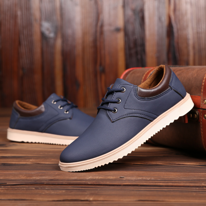Blauwe leren herenschoenen met veters, casual stijl, op houten vloer met vintage koffer. Comfortabele en modieuze schoenen voor dagelijks gebruik.