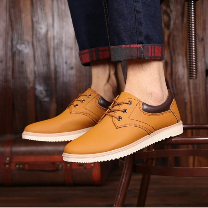 Gele leren herenschoenen met bruine accenten, casual stijl, gedragen met opgerolde jeans. Perfect voor modieuze, comfortabele herenschoenen.