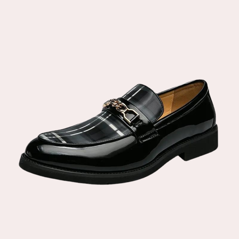 Zwarte leren loafer met geruite details en metalen gesp, stijlvolle herenschoen, geschikt voor formele gelegenheden, modieuze en elegante uitstraling.