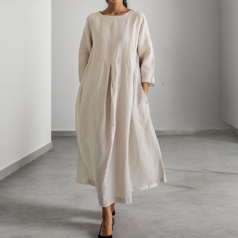 Vrouw in lange, losse, abrikooskleurige linnen jurk met driekwart mouwen, minimalistisch design, casual mode, comfortabele dameskleding.