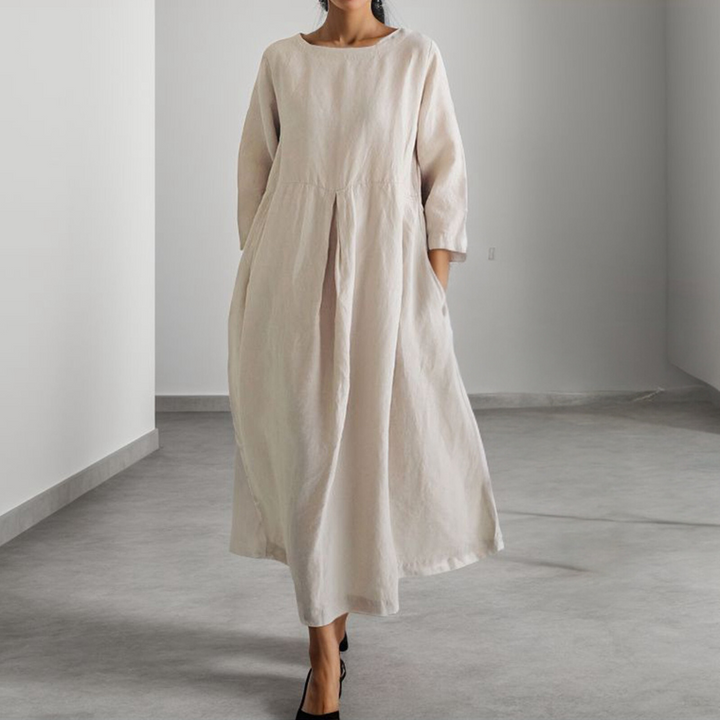 Vrouw in lange, losse, abrikooskleurige linnen jurk met driekwart mouwen, minimalistisch design, casual mode, comfortabele dameskleding.