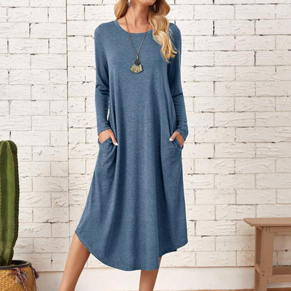Blauwe casual damesjurk met lange mouwen en zakken, gedragen door model. Perfect voor dagelijks gebruik. Comfortabele pasvorm, trendy en stijlvol.