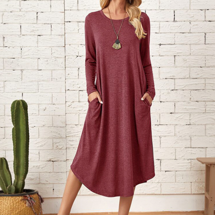 Rode casual jurk met lange mouwen en zakken, gedragen door model voor witte bakstenen muur. Trendy damesmode, comfortabele pasvorm.