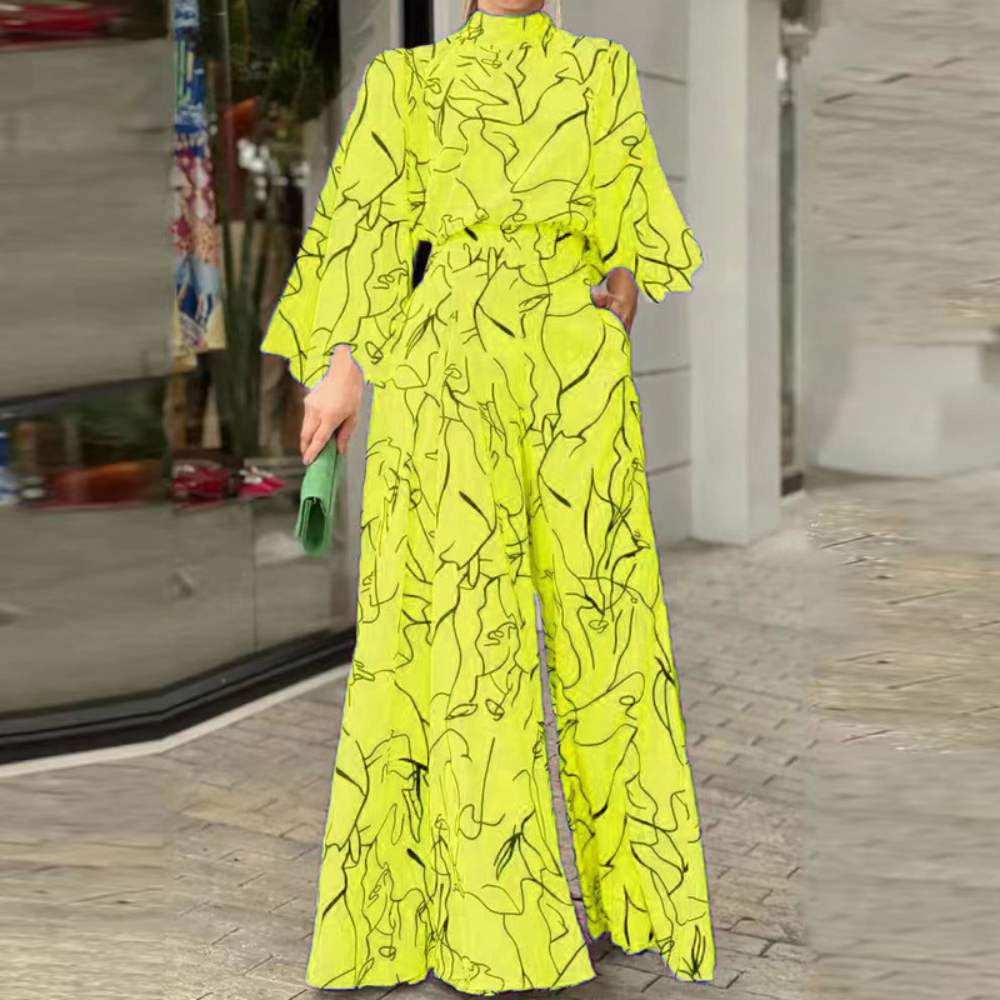 Heldere gele jumpsuit met abstracte zwarte lijnen, wijde pijpen en lange mouwen, gedragen door een persoon voor een winkelraam. Modieuze dameskleding.