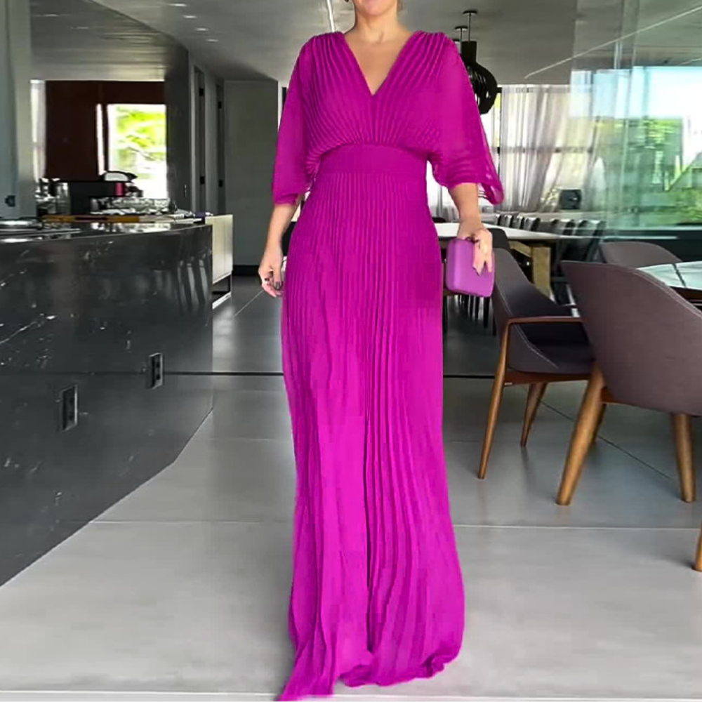 Vrouw in elegante, lange, roze jurk met plooien, staand in moderne woonkamer. Luxe mode, avondkleding, stijlvolle outfit, interieur.