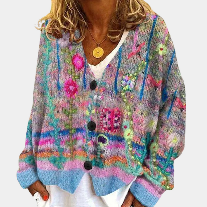 Vrouw draagt kleurrijk gebreid vest met bloemenpatroon en knopen, perfect voor herfstmode. Trendy dameskleding, bohemian stijl, comfortabele pasvorm.