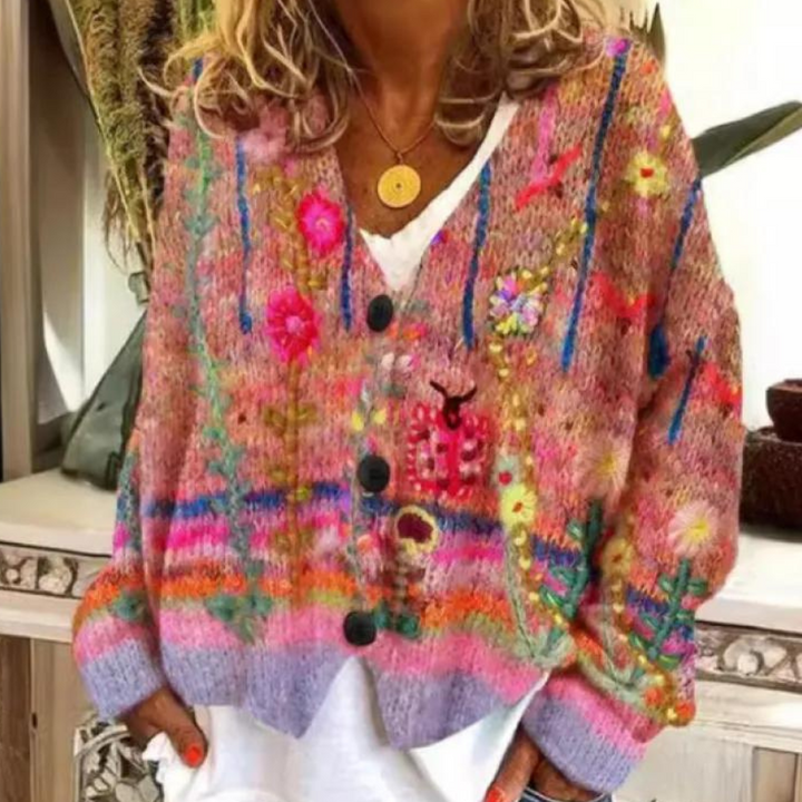 Vrouw draagt kleurrijk gebreid vest met bloemenpatroon en knopen, perfect voor herfstmode. Trendy dameskleding, bohemian stijl, warme tinten.