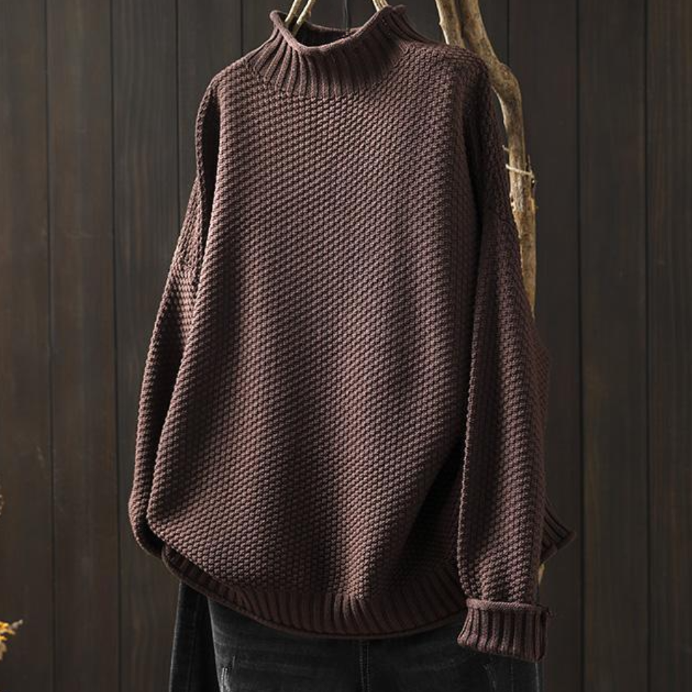 Bruine gebreide trui met hoge kraag, hangend aan een houten hanger. Perfect voor herfstmode, warme kleding, casual stijl.