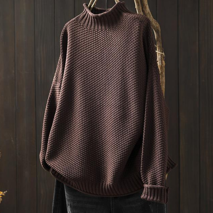 Bruine gebreide trui met hoge kraag, hangend aan een houten hanger. Perfect voor herfstmode, warme kleding, casual stijl.