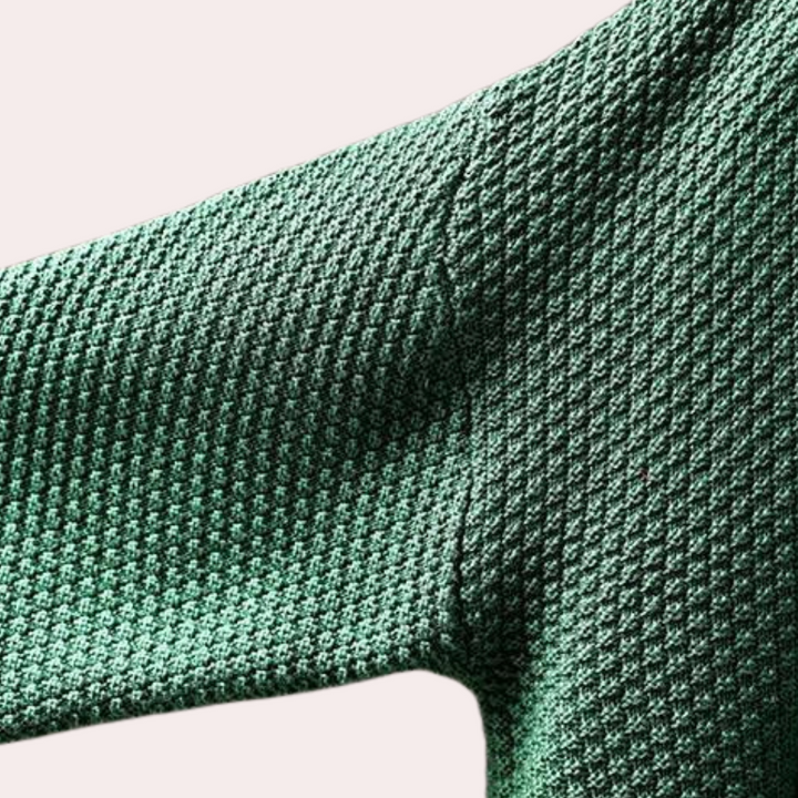 Groene gebreide trui met textuur, close-up van mouwdetail. Modieuze dameskleding, comfortabele stof, trendy design voor herfst en winter.