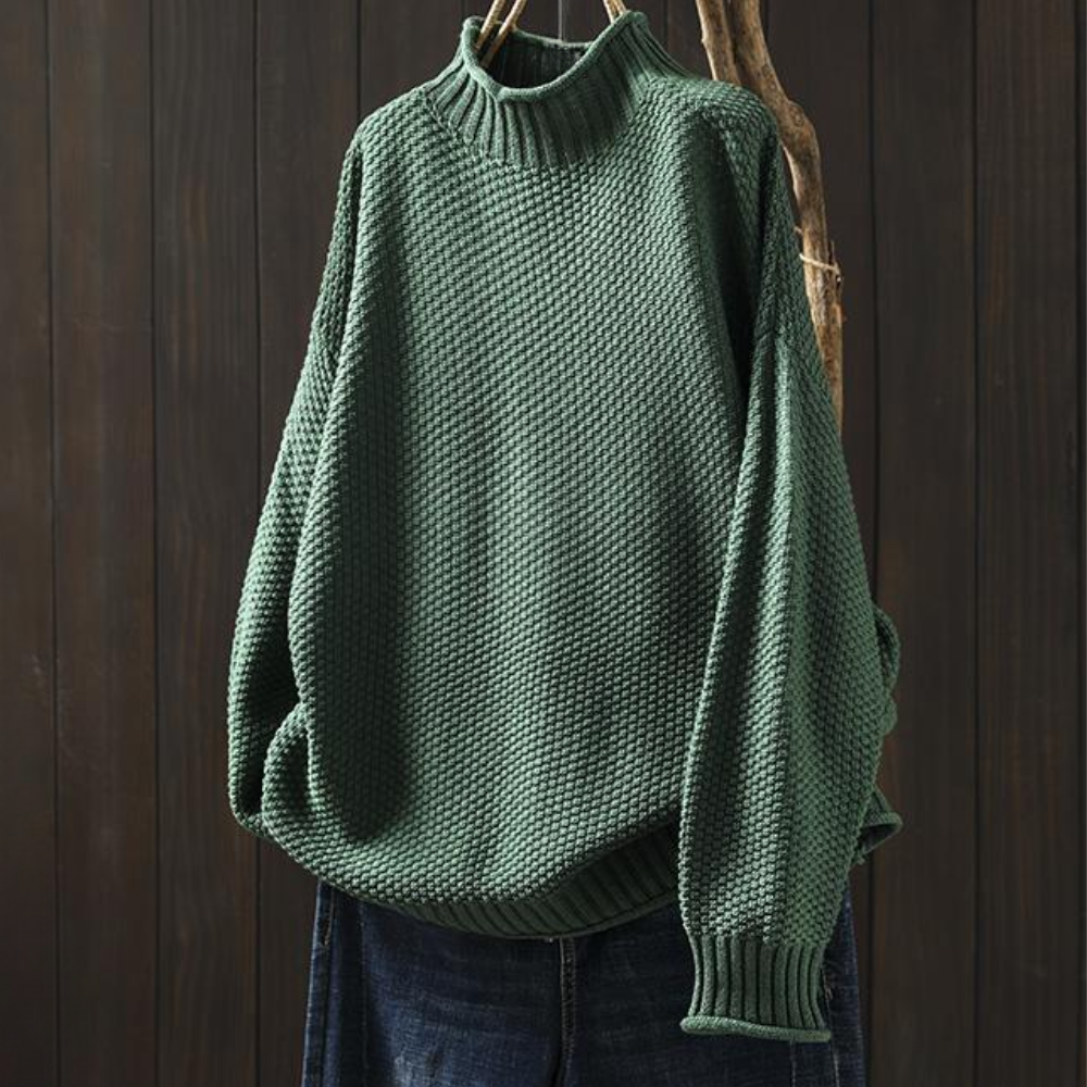 Groene gebreide trui met hoge kraag, textuurpatroon en lange mouwen, hangend voor een houten achtergrond. Perfect voor herfstmode en casual stijl.