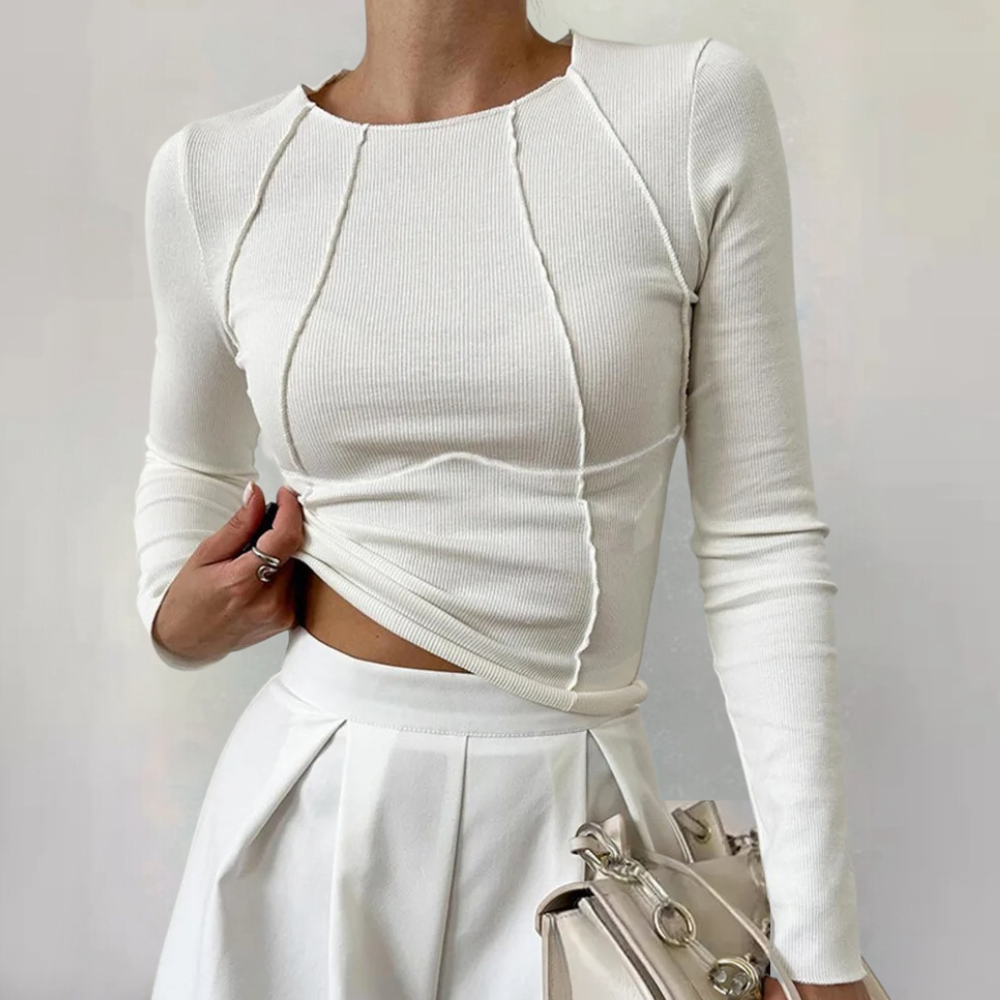 Witte damestrui met lange mouwen en siernaden, gecombineerd met een geplooide witte rok en een beige handtas. Elegante damesmode outfit.