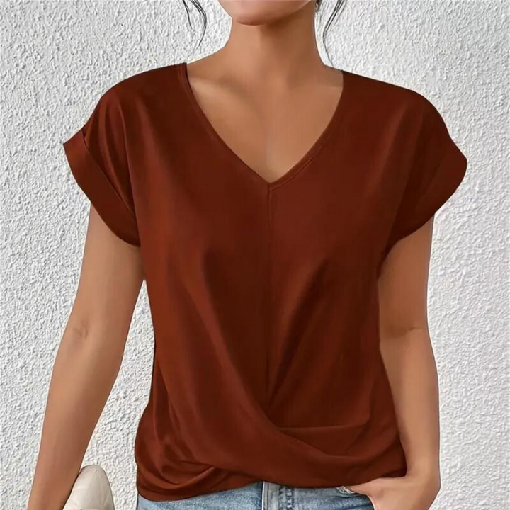 Vrouw draagt bruinrood T-shirt met V-hals en opgerolde mouwen, casual stijl, tegen witte achtergrond. Perfect voor damesmode en casual outfits.