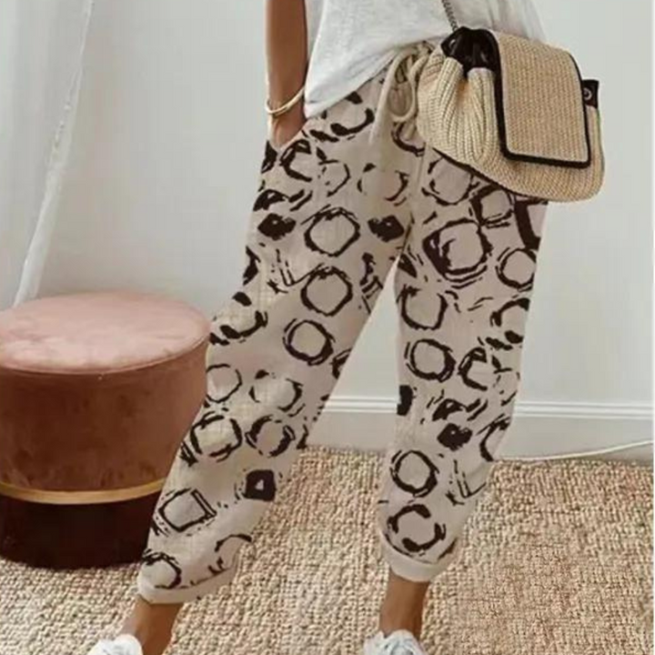 Vrouw in casual outfit met khaki broek met abstracte print en beige geweven tas. Trendy damesmode, comfortabele stijl, zomeroutfit.