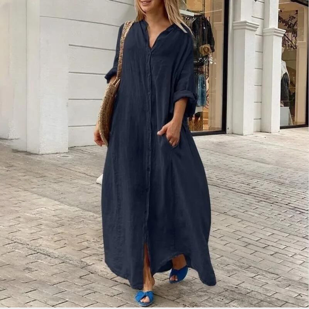 Vrouw in marineblauwe maxi-jurk met opgerolde mouwen, wandelend op straat. Stijlvolle zomeroutfit, casual mode, comfortabele dameskleding.