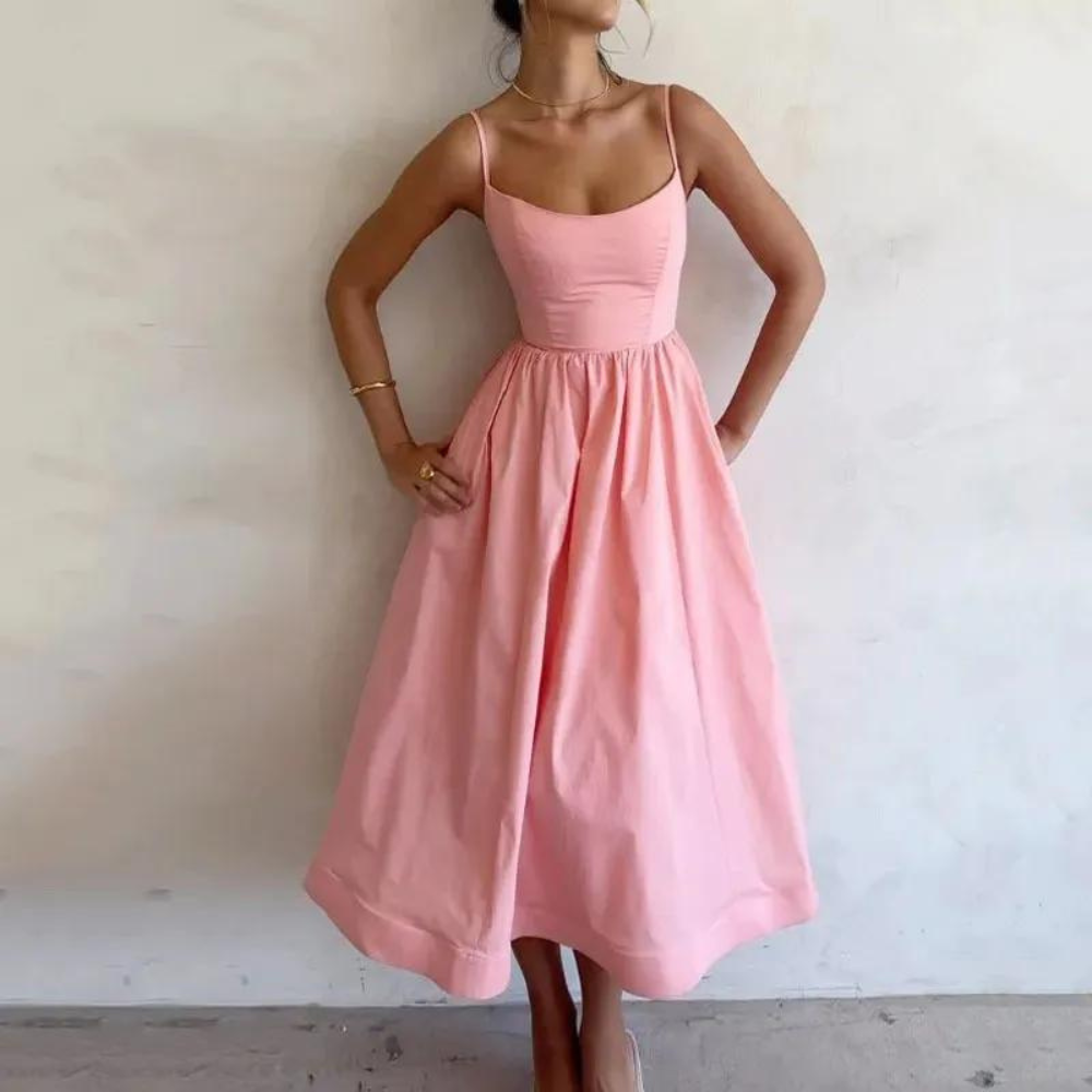Vrouw in roze zomerjurk met spaghettibandjes, elegante pasvorm, casual stijl, perfect voor zomerse gelegenheden en modieuze outfits.
