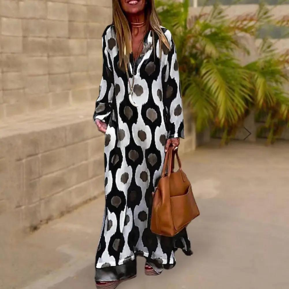 Vrouw in lange, zwart-witte jurk met abstract patroon, draagt bruine handtas. Stijlvolle mode, buitenomgeving, trendy dameskleding.