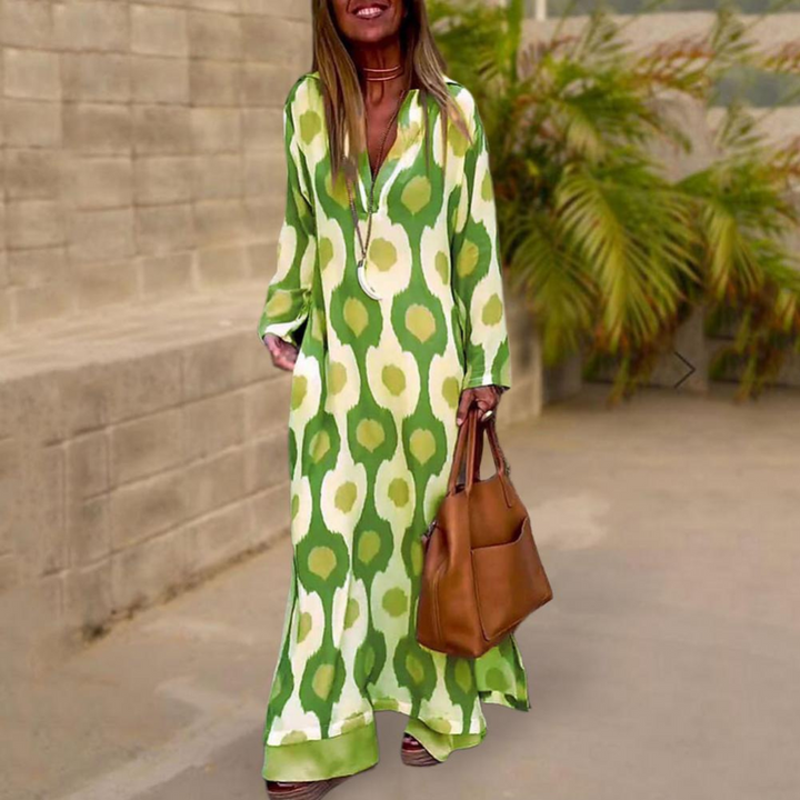 Vrouw in groene maxi-jurk met abstract patroon, draagt bruine handtas. Stijlvolle zomeroutfit, casual mode, buitenomgeving.