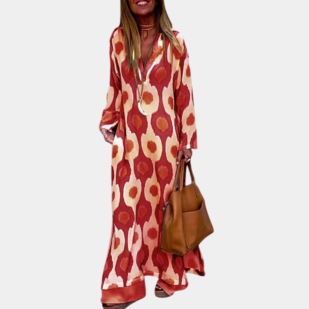 Rode maxi-jurk met abstract patroon, lange mouwen en V-hals. Vrouw draagt bruine leren tas. Trendy damesmode, bohemian stijl.
