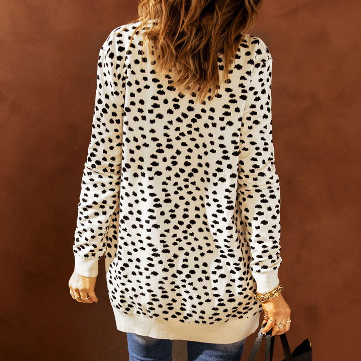 Vrouw in lange, beige trui met zwarte stippen, casual mode, herfstkleding, trendy dameskleding, rugaanzicht, bruine achtergrond.