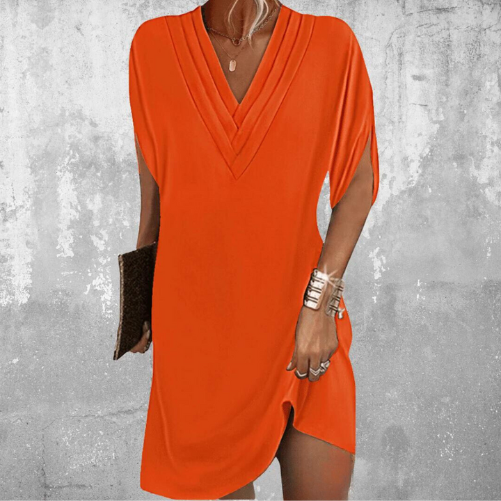 Oranje damesjurk met V-hals, korte mouwen en split, gedragen door model. Perfect voor zomer, casual en strand. Trendy en stijlvol design.