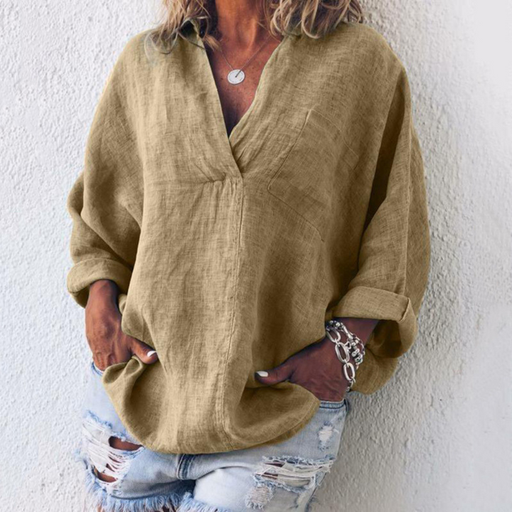 Vrouw draagt een oversized khaki linnen blouse met opgerolde mouwen, gecombineerd met gescheurde denim shorts. Casual en modieuze dameskleding.