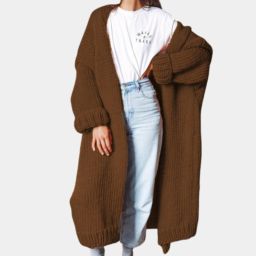 Vrouw in bruine gebreide lange cardigan, witte T-shirt en blauwe jeans. Modieuze herfstoutfit, comfortabele dameskleding, casual stijl.