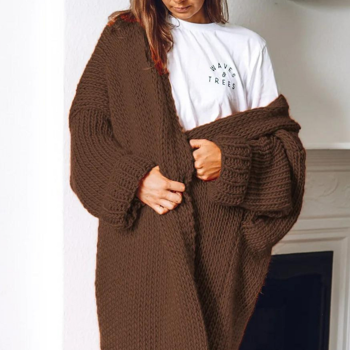 Vrouw draagt een oversized, bruin gebreid vest over een witte T-shirt met opdruk. Comfortabele herfstmode, casual stijl, warme kleding.