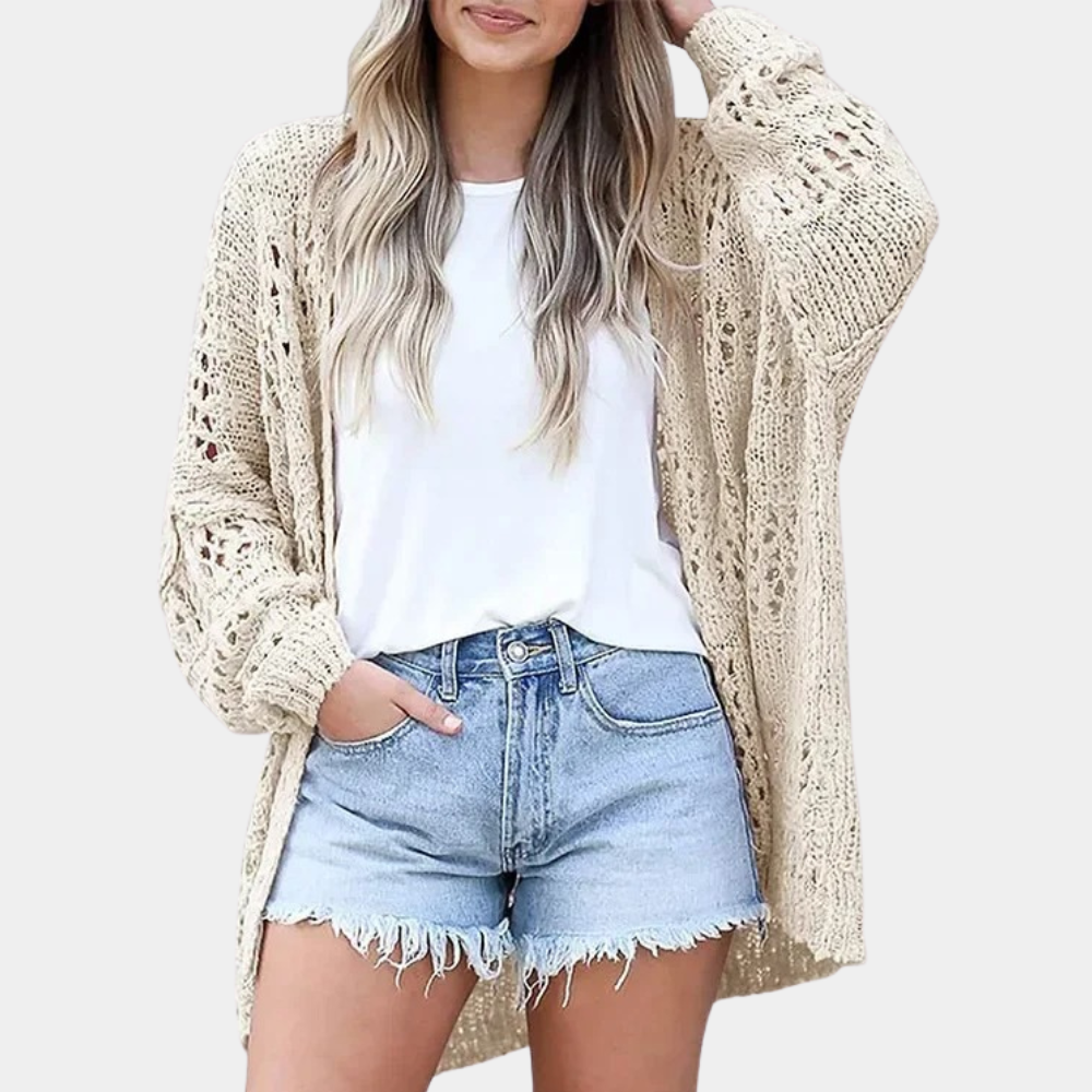 Vrouw draagt beige gehaakt vest, witte top en denim shorts. Casual zomeroutfit, modetrend, comfortabele dameskleding.