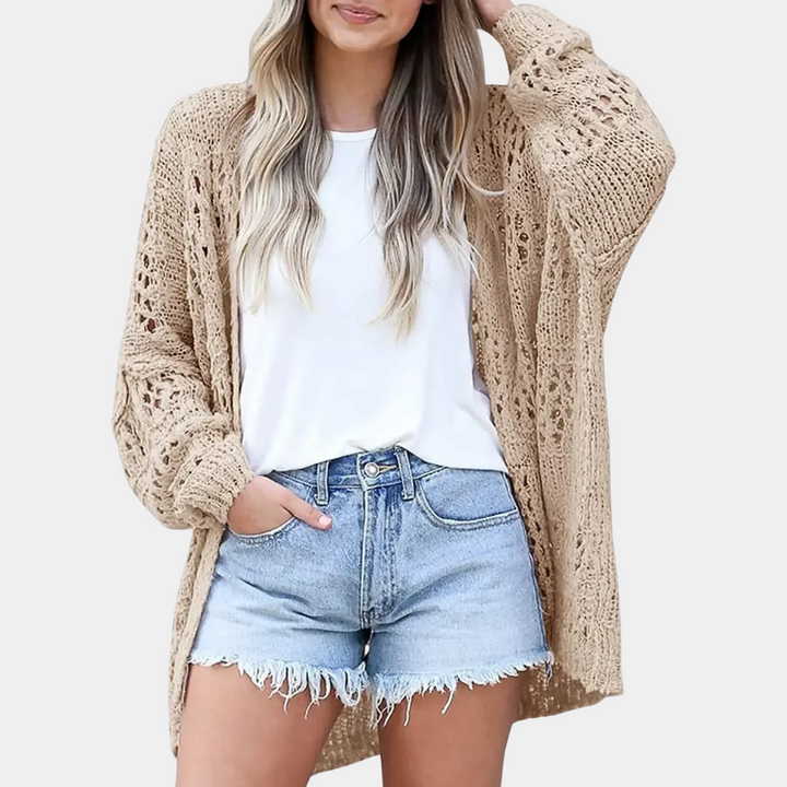 Vrouw draagt een khaki gehaakte cardigan, witte T-shirt en denim shorts. Casual zomeroutfit, modetrend, comfortabele dameskleding.
